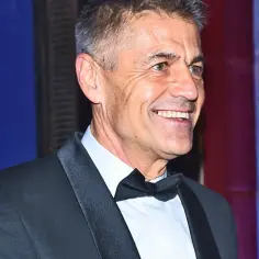 Uśmiechnięty Krzysztof Hołowczyc w smokingu. Wiek nie jest przeszkodą w elegancji.