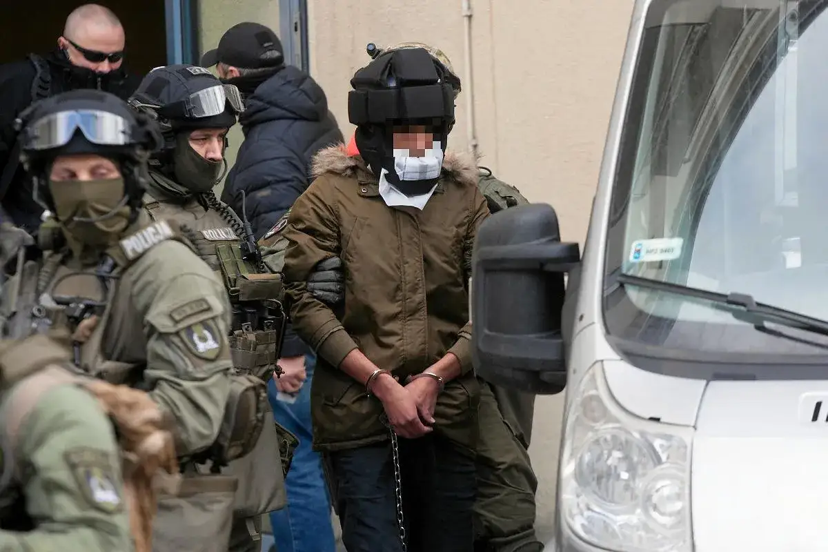 Kajetan Poznański w kajdankach, eskortowany przez policję.