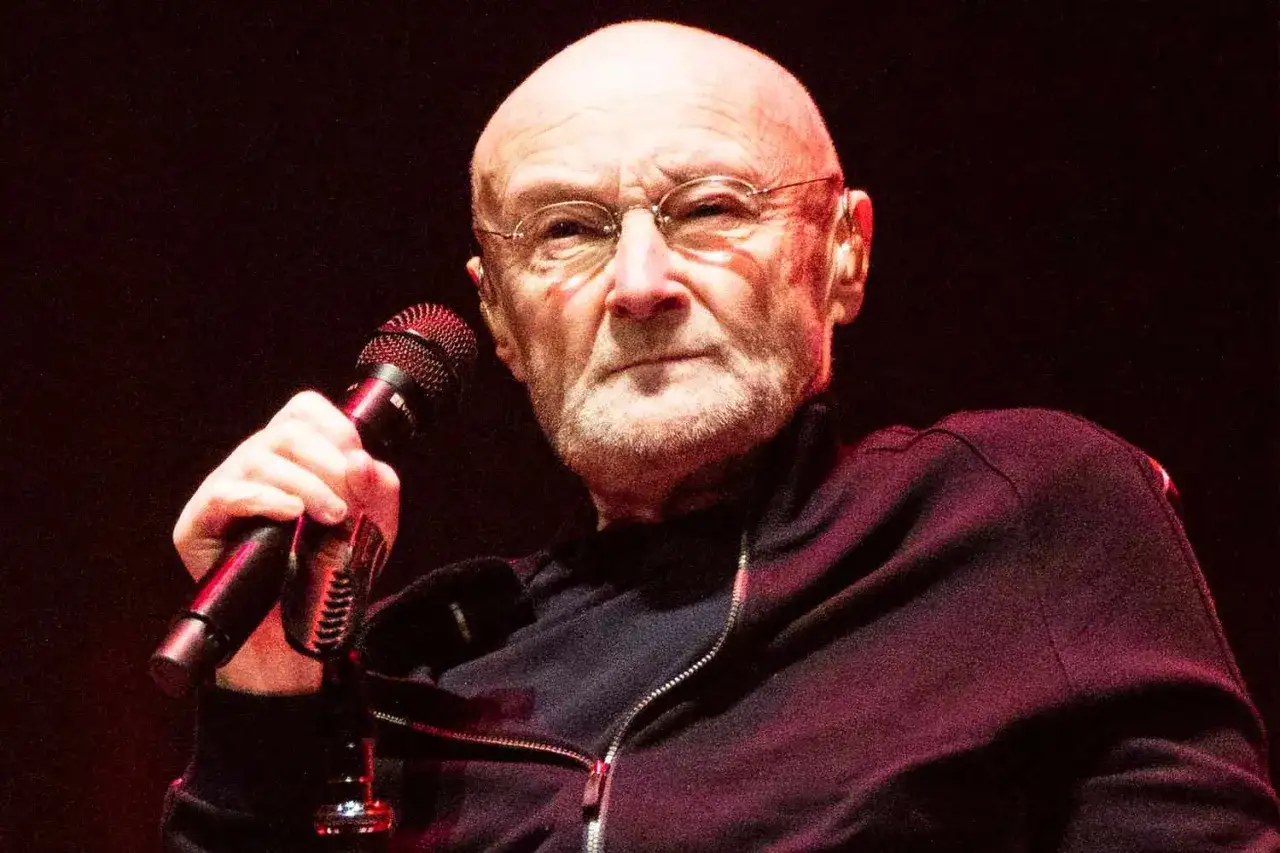 Phil Collins, mimo choroby, wciąż śpiewa do mikrofonu, emanując siłą sceniczną.